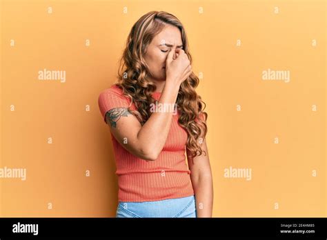 Jeune fille blonde portant des vêtements décontractés fatigués frottant le nez et les yeux