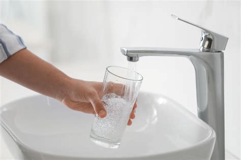 Premium Photo Woman Filling Glass With Water From Faucet Over Sink