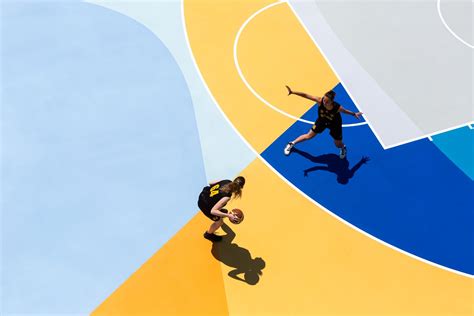 Two People Are Playing Basketball On A Colorful Court With Blue And