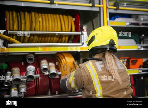 A Female Firefighter Prepares Equipment On A Fire Engine During A