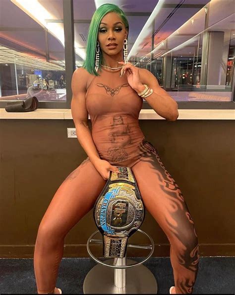 A Woman With Green Hair And Tattoos Sitting On Top Of A Metal Pole In