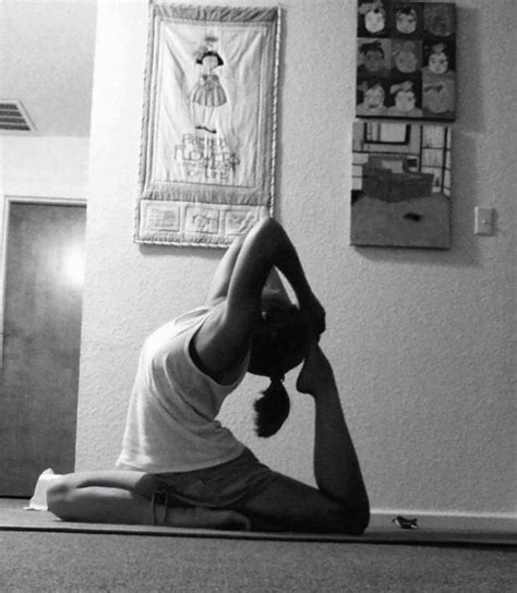 A Woman Is Doing Yoga In Front Of A Wall With Pictures On The Wall