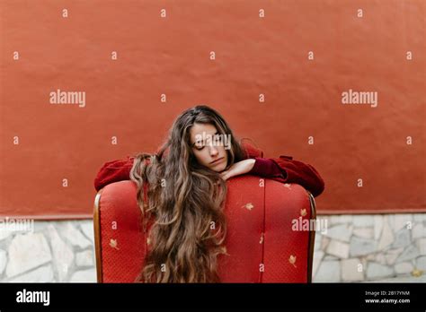 Portrait Of Young Woman With Long Brown Hair Leaning On Back Rest Of