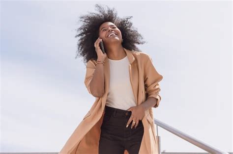 Joven latina hispana feliz con afro al aire libre hablando por teléfono y sonriendo Foto Premium