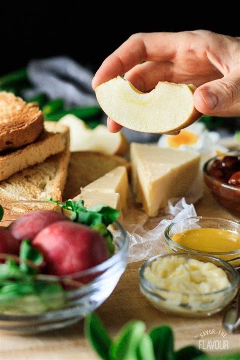 A Person Is Holding An Apple Slice Over Some Bread And Other Food On A