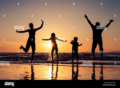 Silhouette d une famille heureuse qui jouent sur la plage à l heure du