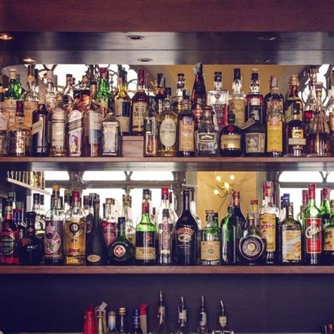 a bar with lots of liquor bottles and glasses on the shelves above it, all lined up in rows