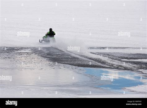 Snowmobile racing across an open patch of water on Lake Pleasant, NY in ...