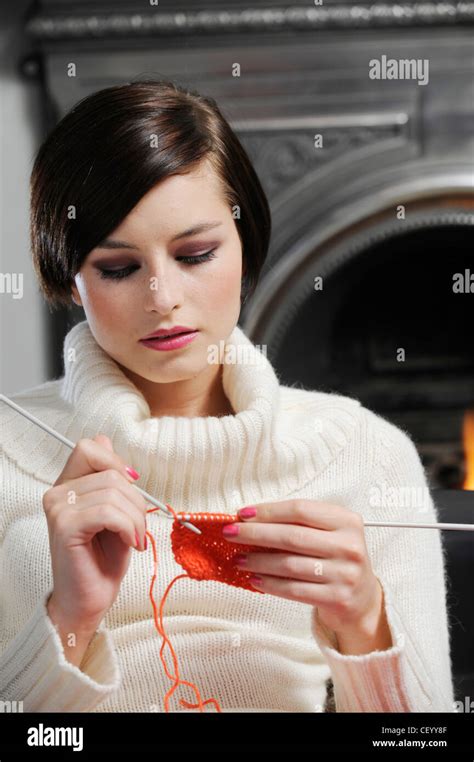 Female With Short Brunette Hair Wearing A White Jumper Sitting By The