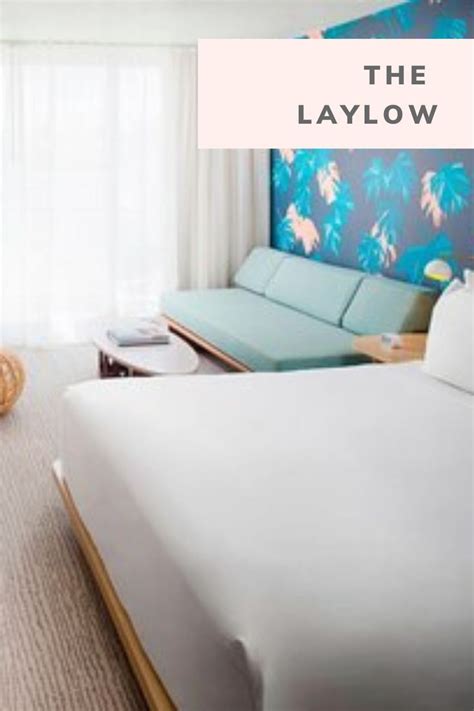 A Hotel Room With A Bed Couch And Television In It That Says The Laylow