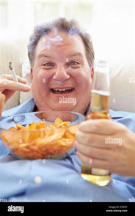 Overweight Man Eating Chips Drinking Beer And Smoking Stock Photo Alamy