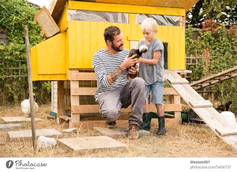 Vater und Sohn mit polnischen Hühnern im Hühnerstall im Garten ein