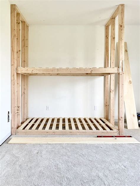 A Wooden Bed Frame Sitting In The Middle Of A Room With Carpet On The Floor