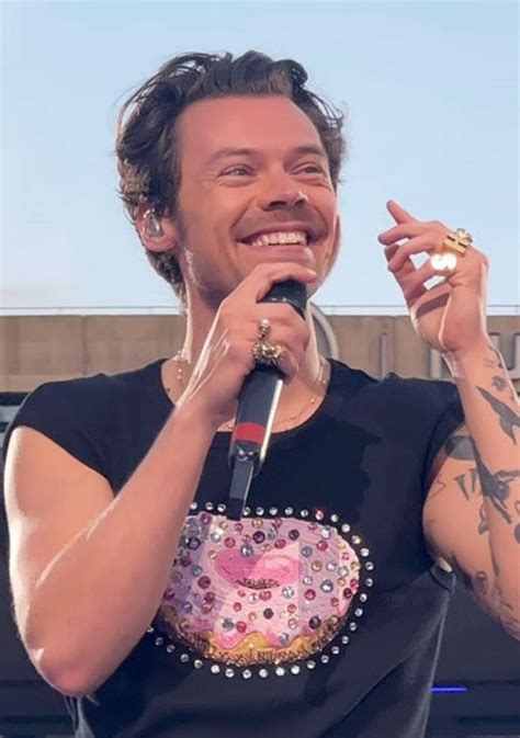 A Man Holding A Microphone In His Right Hand And Wearing A Black Shirt