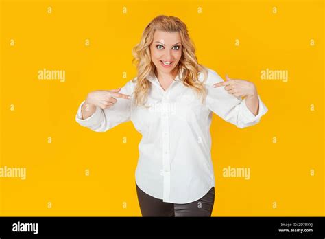 Erstaunt sprachlos beeindruckt glücklich europäische blonde Frau in weißem Hemd zeigt auf sich