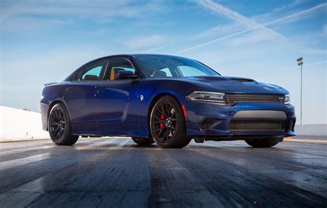 A Blue Dodge Charger Parked In An Empty Parking Lot With The Sky And