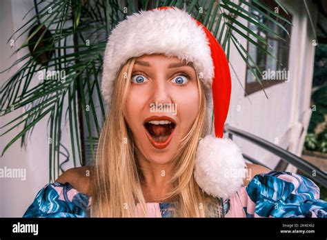 Funny Shocked Blonde Woman Wearing Santa Hat Looking Into Camera With