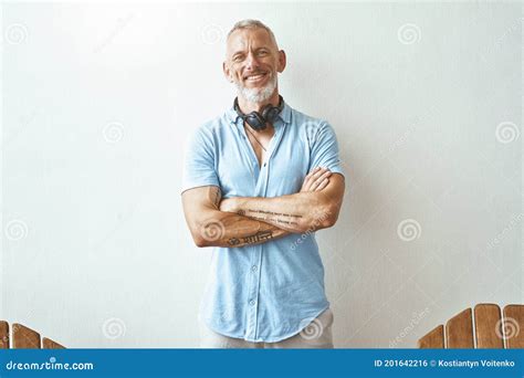 Portrait Of A Happy Middle Aged Caucasian Man Keeping Arms Crossed And Smiling At Camera While