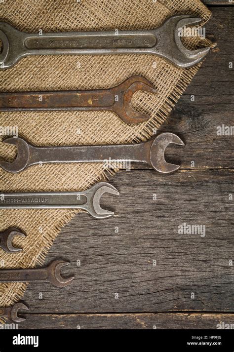 Old And Rusty Spanners On A Background Of A Wooden Table And Sacking