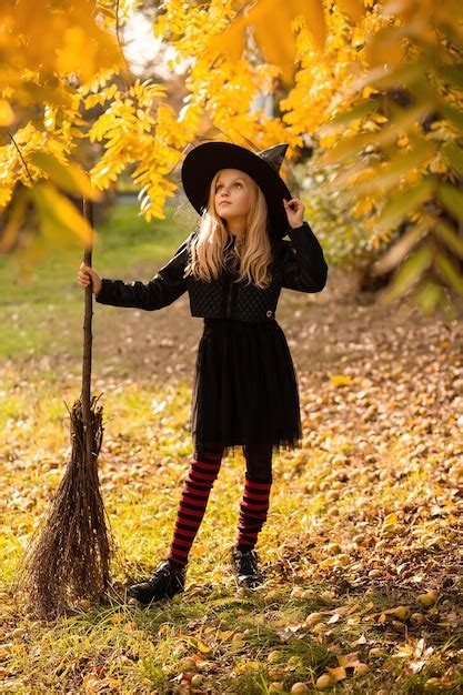 Premium Photo A Girl In A Witch Costume Stands With A Broom Holding