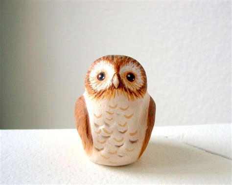 An Owl Figurine Sitting On Top Of A White Table Next To A Wall