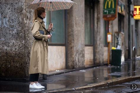 A Woman Standing In The Rain Holding An Umbrella And Looking At