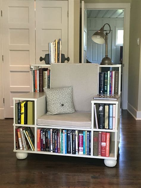 A White Chair Sitting In Front Of A Book Shelf Filled With Books