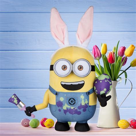 a minion with bunny ears holding a paintbrush and some easter eggs in front of it