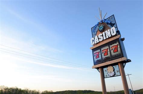 a casino sign in front of a blue sky and some trees on the other side