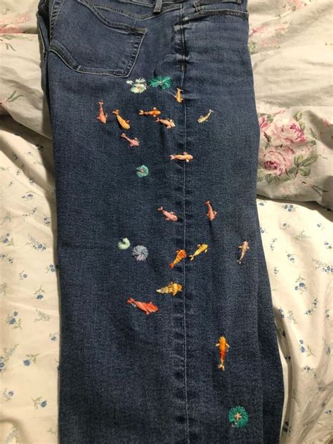 An Embroidered Pair Of Jeans With Fish On The Side And Flowers All Over