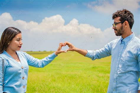 Happy couple making a heart shape with their hands, couple in love in the field making a heart ...