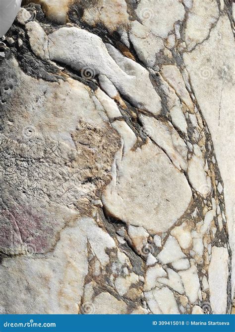 The Texture Of An Old Stone Wall With Pieces Of White Marble And Gray