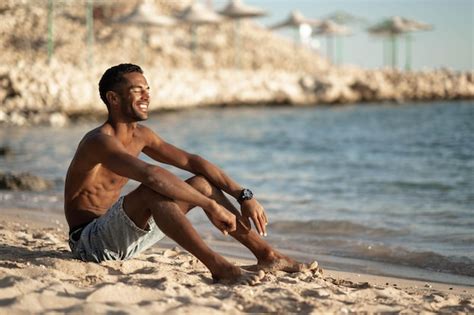 Premium Photo | Side view of young man sitting at beach