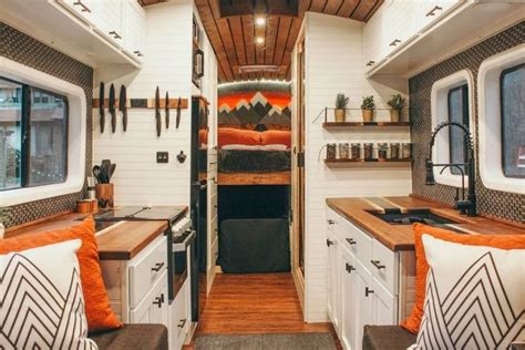 the interior of a small camper with wood flooring and white cupboards ...