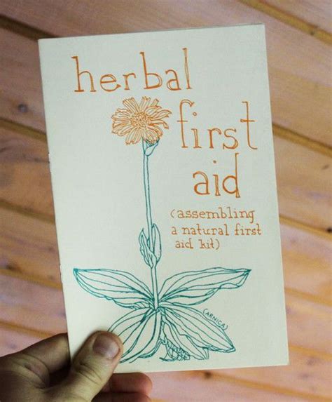 A Person Holding Up A Card With The Words Herb First Aid On It