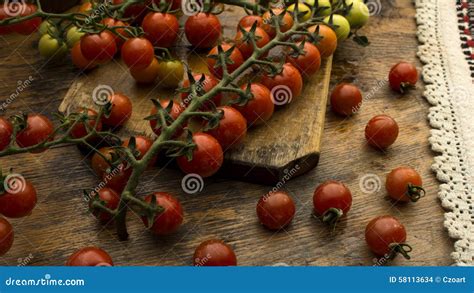 Tomates De Cereza En La Tajadera Y La Tabla De Madera Foto De Archivo