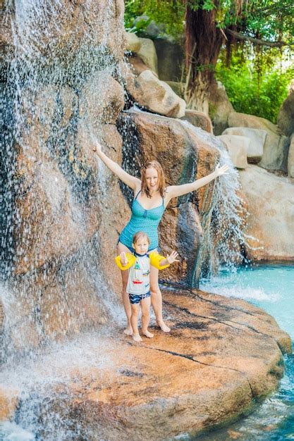 Madre e hijo relajándose bajo una cascada en el parque acuático Foto