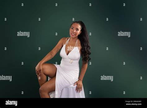 Beautiful Brunette Woman Sitting With Hands On Her Knees Posing For Photo Isolated On Green