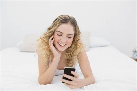 Premium Photo Pretty Smiling Blonde Lying On Bed Using Smartphone