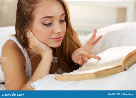 Jeune Belle Femme Blonde De Sourire Se Situant Dans La Lecture De Lit