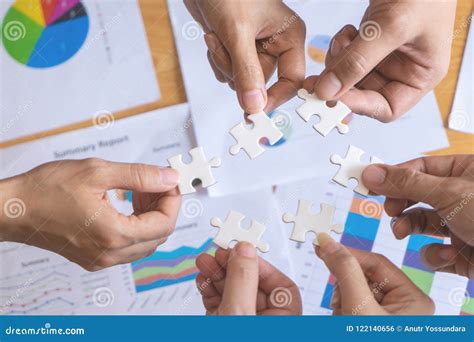 Team Placing Puzzles Jigsaw Together For Team Concept Stock Photo