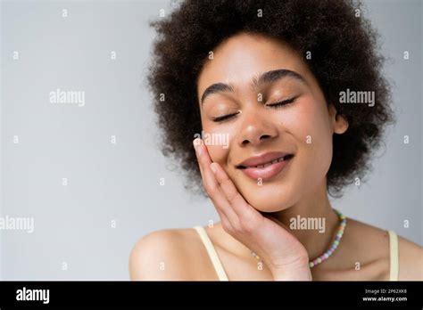 Portrait Of Smiling African American Woman Touching Face Isolated On