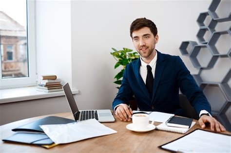 Hombre De Negocios Acertado Joven Que Se Sienta En El Lugar De Trabajo