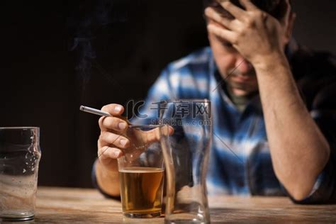 酒精中毒、酒精成瘾和人的观念 男性酗酒者在晚上喝啤酒和抽烟的特写。高清摄影大图 千库网