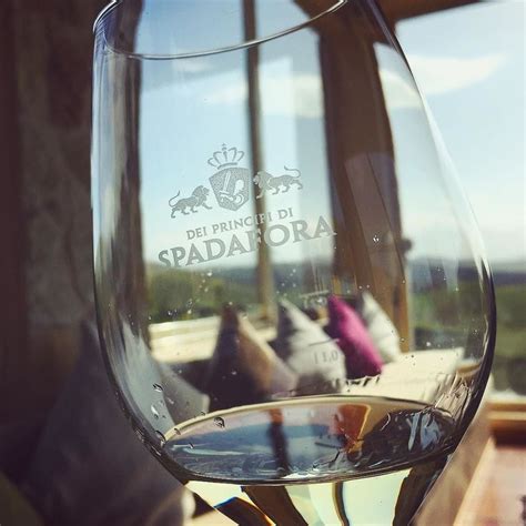 A Glass Of Wine Sitting On Top Of A Wooden Table Next To A Window With