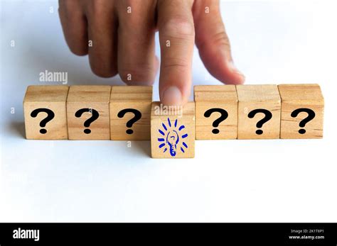 Hand Pushing Wooden Cube Block With Light Bulb Surrounded By Questions