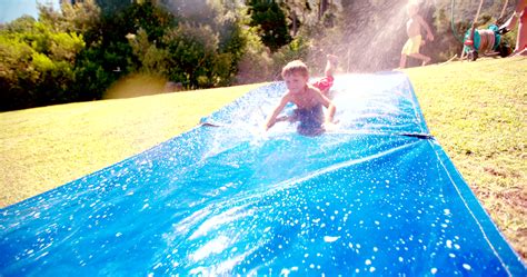 Niño deslizándose por un tobogán de agua resbaladizo al aire libre