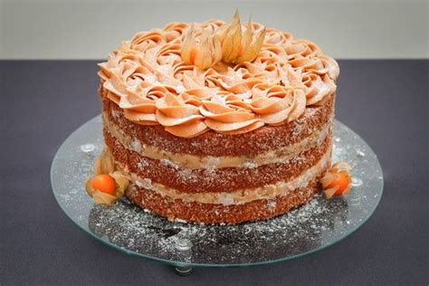 A Three Layer Cake With Frosting And Orange Flowers On A Glass Plate