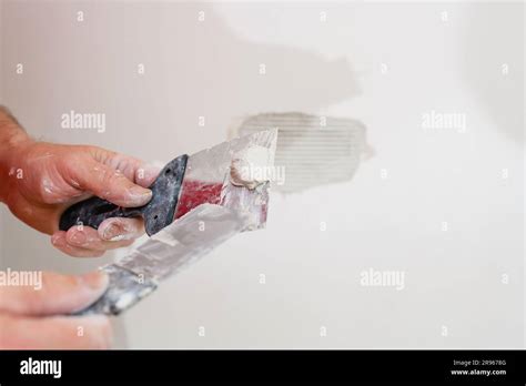 Repairing Holes In Drywall A Handyman Is Repairing A Hole In The