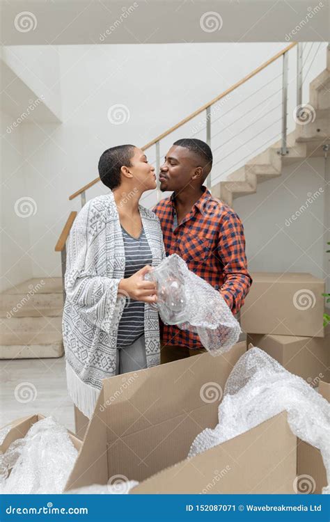 Couple Kissing Each Other While Unpacking Cardboard Boxes In Living